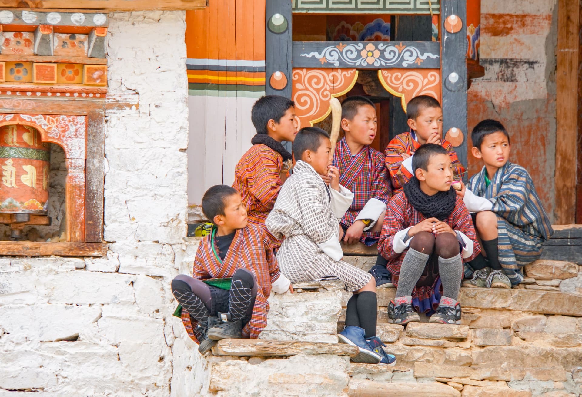 Bhutan Travel Guide Young bhutanese boys in traditional clothing sit to watch the festival. Trips At Asia.